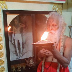 H. H. Swami Krishnananda Saraswathi, seniormost disciple of Jagadguru Sathyananda Swamikal. At Ramagiri. The picture of Gurupadar is drawn with coal. Swamiji says, 